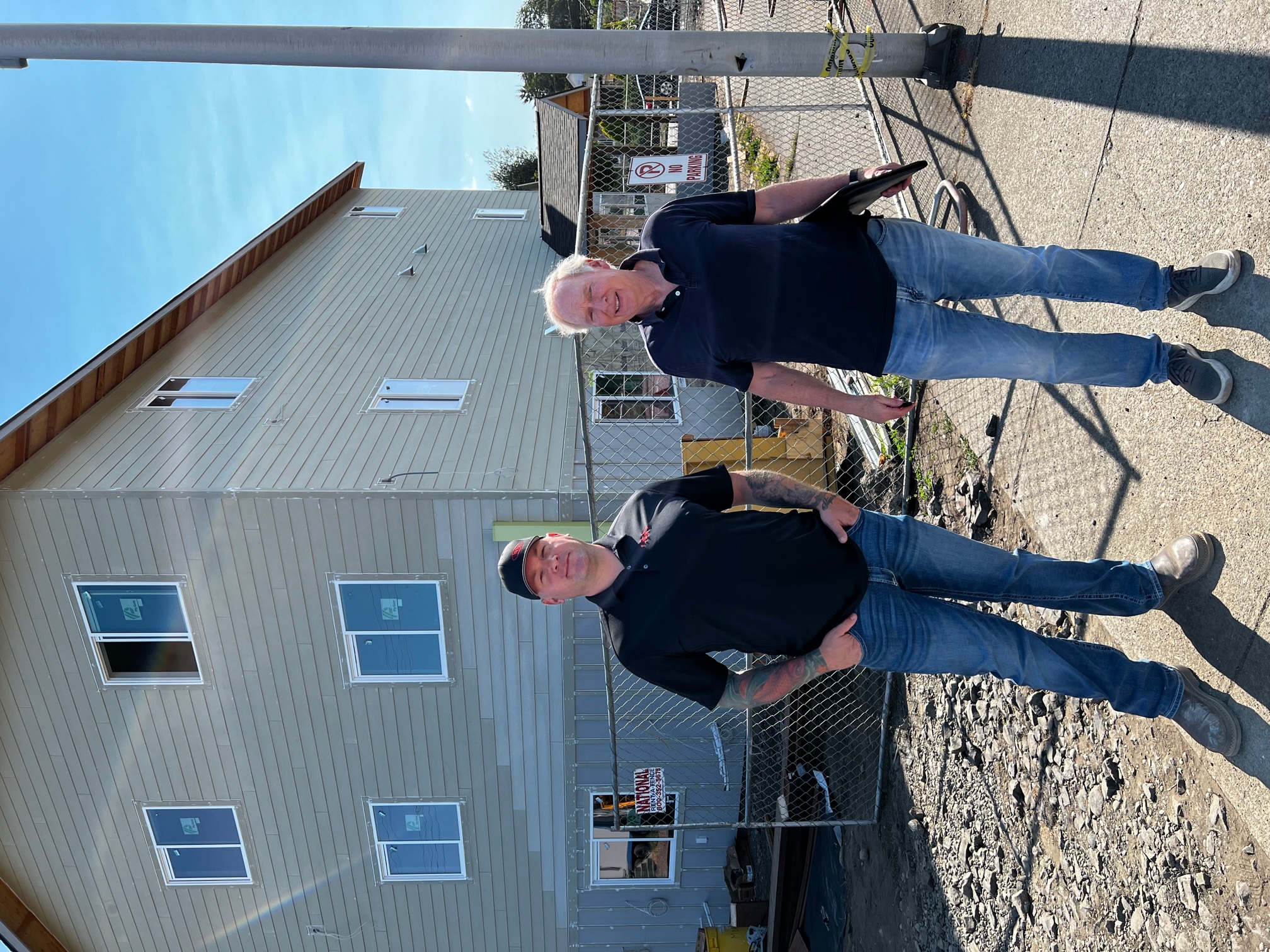 Owner and chief contractor in front of section of three-story building.